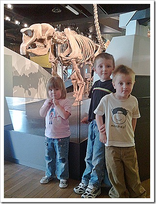 Kids in front of a dinosaur.