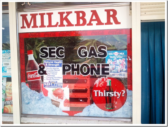A sign for SEC, Gas and Phone on the outside of a milk bar.
