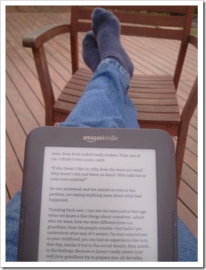 Reading a Kindle with feet up on a chair.
